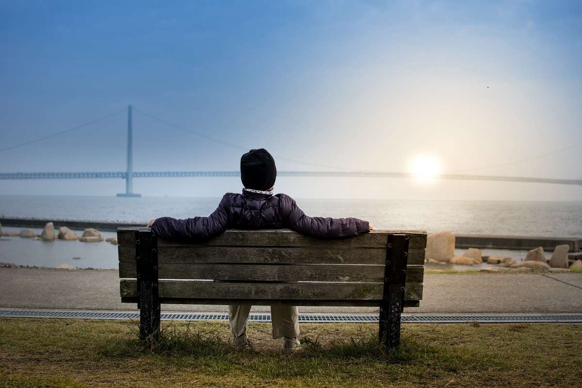 Man sitting on a bench - relaxing - indicative of man who retired early and is enjoying his life